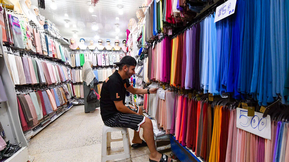 Un vendedor coloca textiles en su tienda en un mercado de Argel - PHOTO / AFP