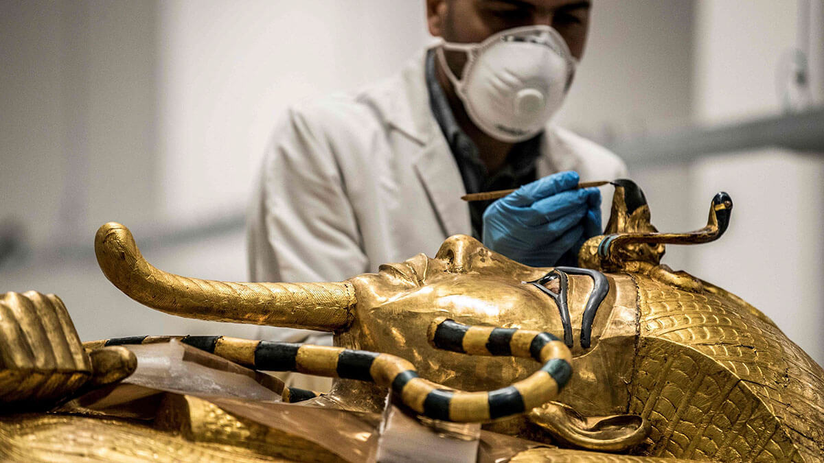 Un arqueólogo egipcio, con equipo de protección personal, realiza restauraciones en el sarcófago dorado del antiguo faraón egipcio Tutankamón (que reinó entre 1342 y 1325 a. C.) en el laboratorio de restauración del recién construido Gran Museo Egipcio (GEM) en Giza - AFP/ KHALED DESOUKI