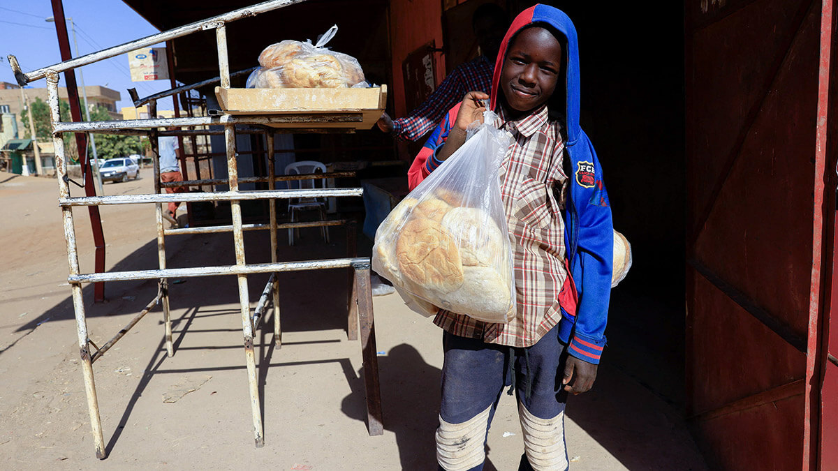 Un niño lleva una bolsa de pan en Jartum, Sudán - REUTERS/ MOHAMED NURELDIN