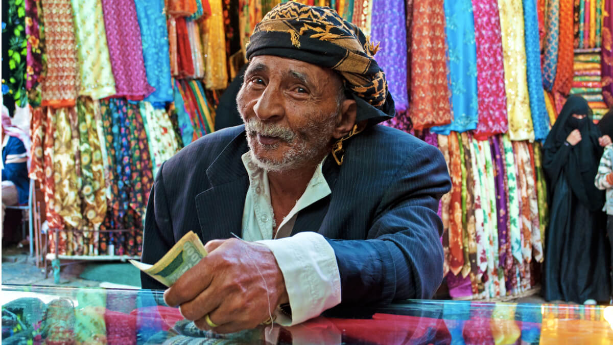Ciudadano yemení pagando con riales en un puesto de la ciudad de Saná - <a  data-cke-saved-href="https://depositphotos.com/es/?/" href="https://depositphotos.com/es/?/">Depositphotos</a>