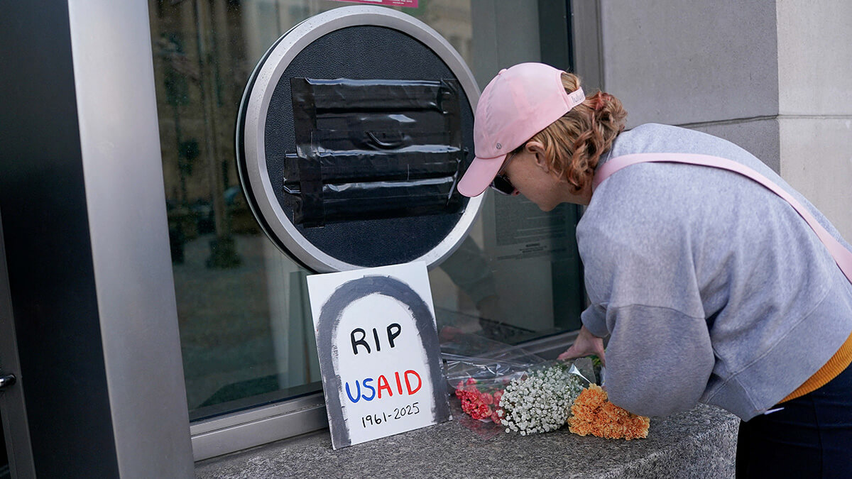 Una persona deja flores, junto a un cartel de USAID que está cubierto, en la sede de la agencia en Washington, EE. UU., el 7 de febrero de 2025 - REUTERS/NATHAN HOWARD
