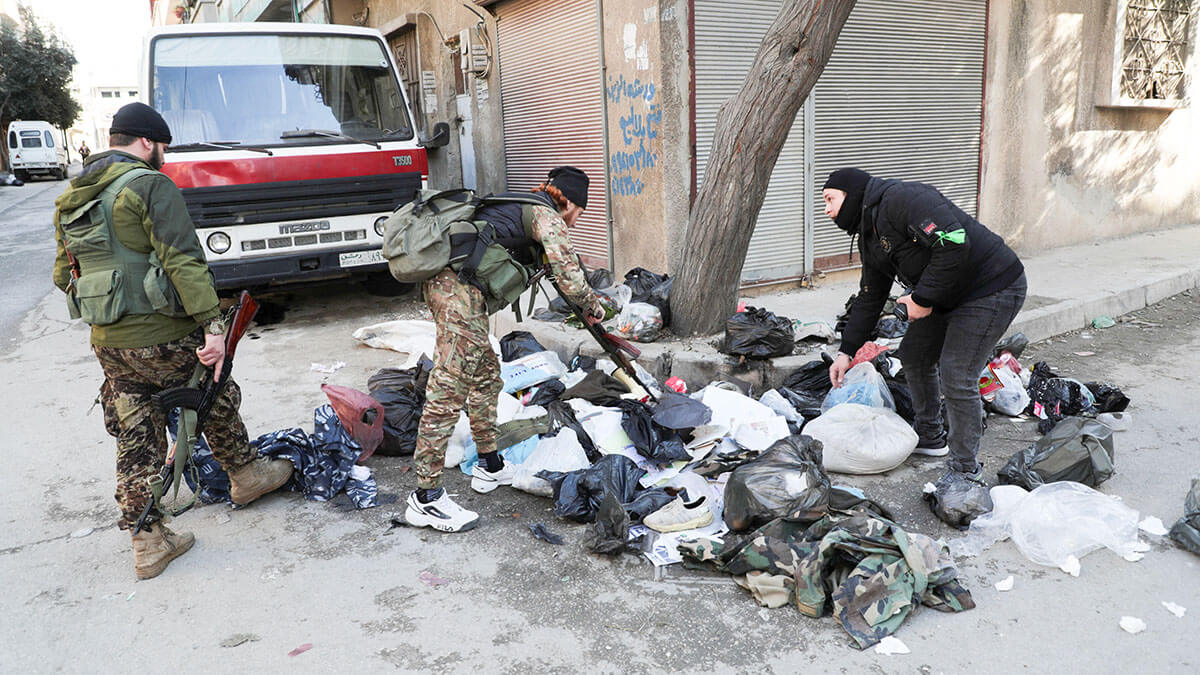 <p>Combatientes de Hayat Tahrir al-Sham (HTS) buscan armas en montones de basura durante lo que dijeron eran controles de seguridad para encontrar restos de la fuerza del derrocado presidente sirio Bashar al-Assad, en el barrio de Wadi al-Dahab en Homs, Siria - REUTERS/ KHALIL ASHAWI</p>