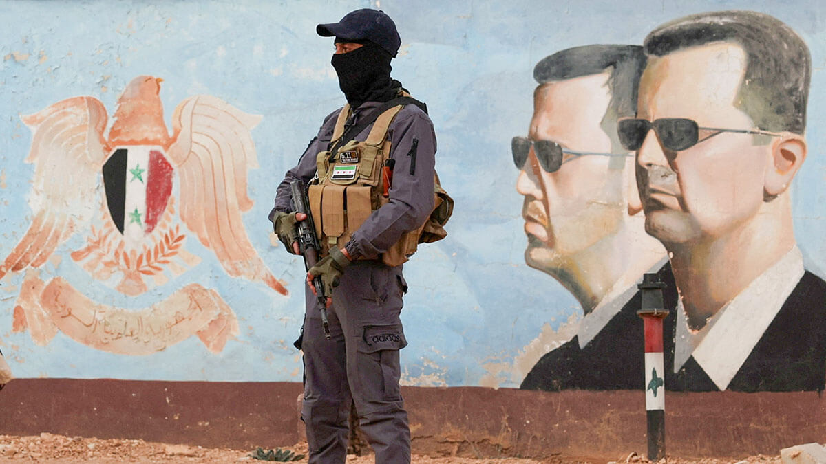 Un miembro del antiguo grupo rebelde Hayat Tahrir al-Sham hace guardia cerca de una imagen del sirio Bashar al-Assad en la sede de la cuarta división en Damasco, Siria, el 23 de enero de 2025 - REUTERS/YAMAM AL SHAAR