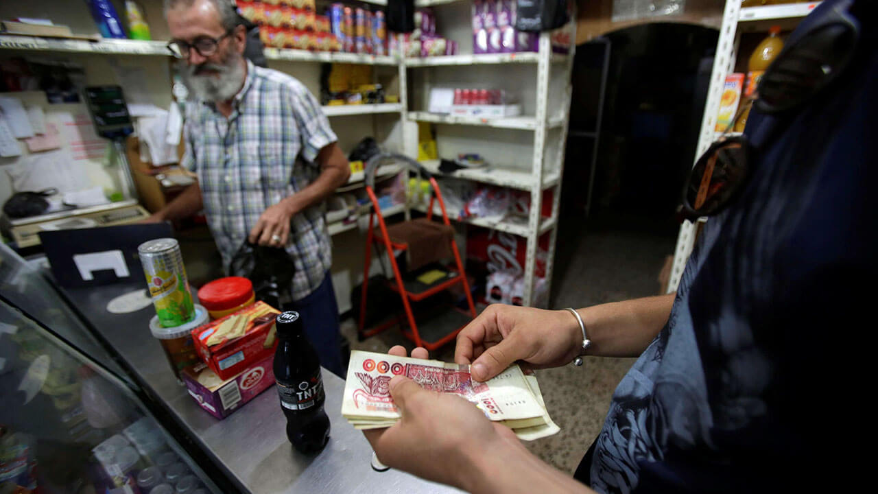 Un cliente le da dinero a un vendedor en una tienda de comestibles en Argel - REUTERS/ RAMZI BOUDINA
