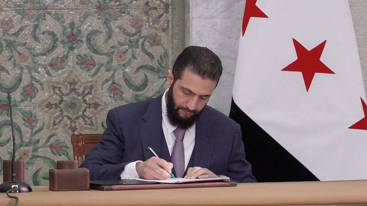 El presidente interino sirio, Ahmed Al-Sharaa, firma un borrador de constitución, tras ser presentado por un comité sirio de expertos legales, en Damasco, Siria, el 13 de marzo de 2025 - PHOTO/ Presidencia siria vía REUTERS TV