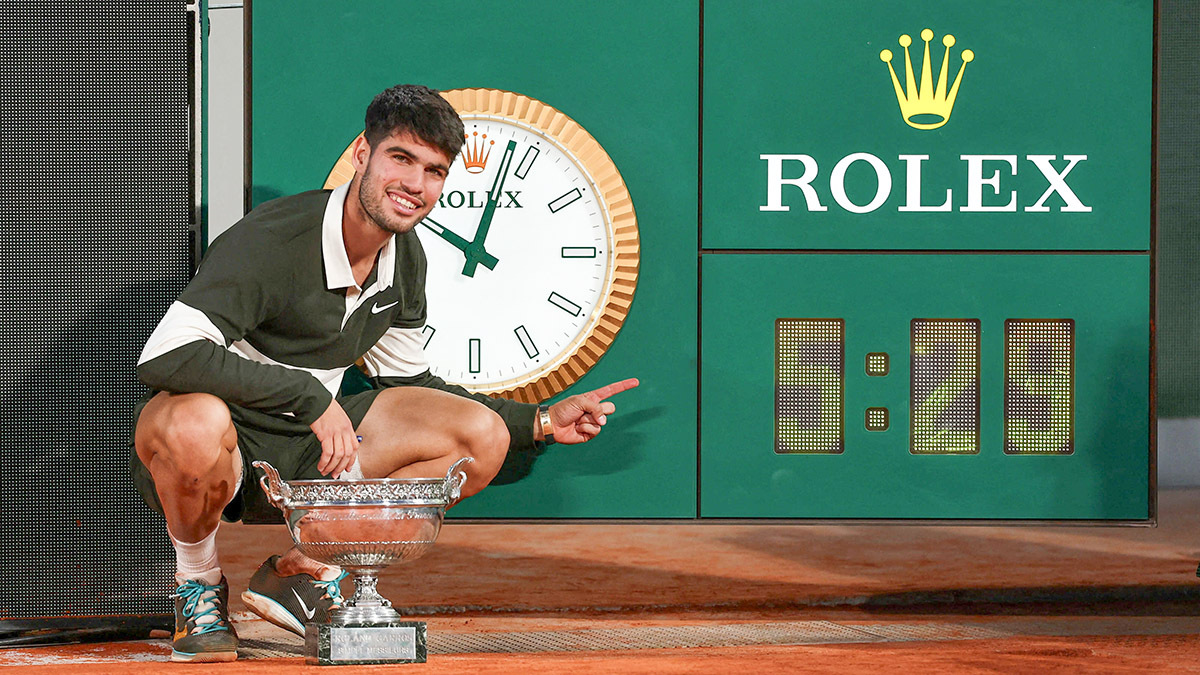 El español Carlos Alcaraz posa con el trofeo mientras señala el reloj después de jugar la final individual masculina más larga de la historia en Roland Garros - REUTERS/ GONZALO FUENTES