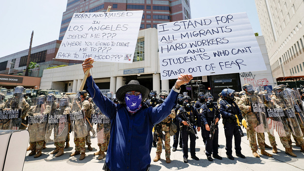 <p>Un manifestante sostiene carteles durante una protesta contra las redadas federales de inmigración, mientras miembros de la Guardia Nacional de California se encuentran afuera del edificio federal Edward R. Roybal - REUTERS/MIKE BLAKE </p>