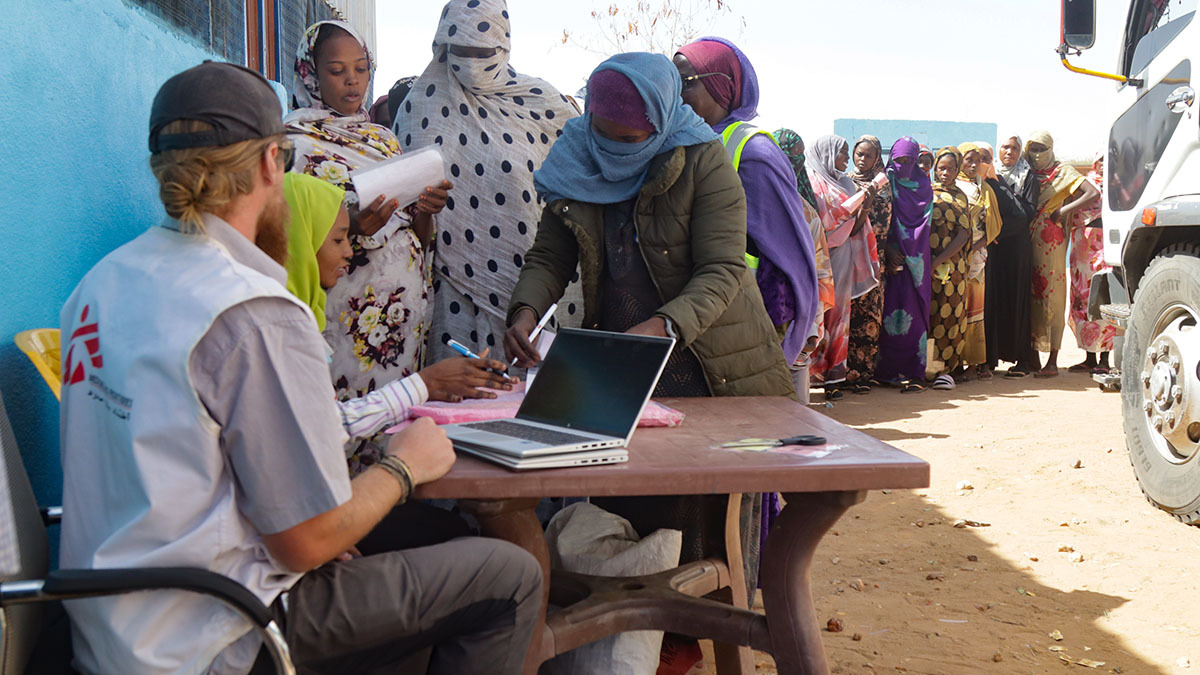 Un miembro del personal de MSF comprueba que las personas están inscritas en nuestros programas antes de entregarles un vale para recibir su cesta de alimentos - PHOTO/ ABDOALSALAM ABDALLAH/ MSF
