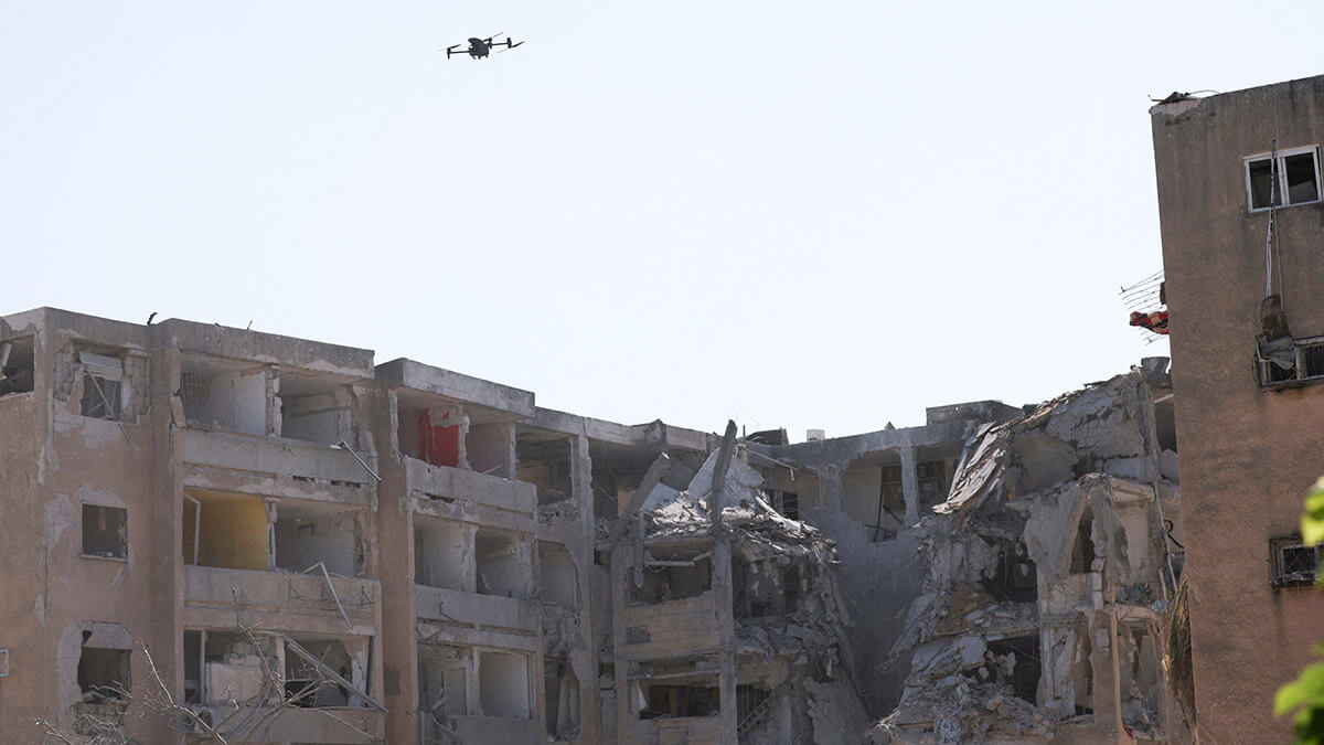 Un dron vuela junto a edificios dañados en el lugar del impacto de un misil iraní contra Israel, en Holon, Israel, el 19 de junio de 2025 - REUTERS/ VIOLETA SANTAS MOURA