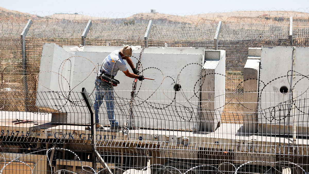 <p>Un trabajador desata muros de hormigón que se colocarán cerca de una puerta en la frontera entre Israel y Siria mediante una maquinaria, a lo largo de la línea de alto el fuego entre los Altos del Golán ocupados por Israel y Siria, en medio del conflicto en curso en las zonas drusas de Siria, en Majdal Shams, el 17 de julio de 2025 - REUTERS/ AMMAR AWAD </p>
