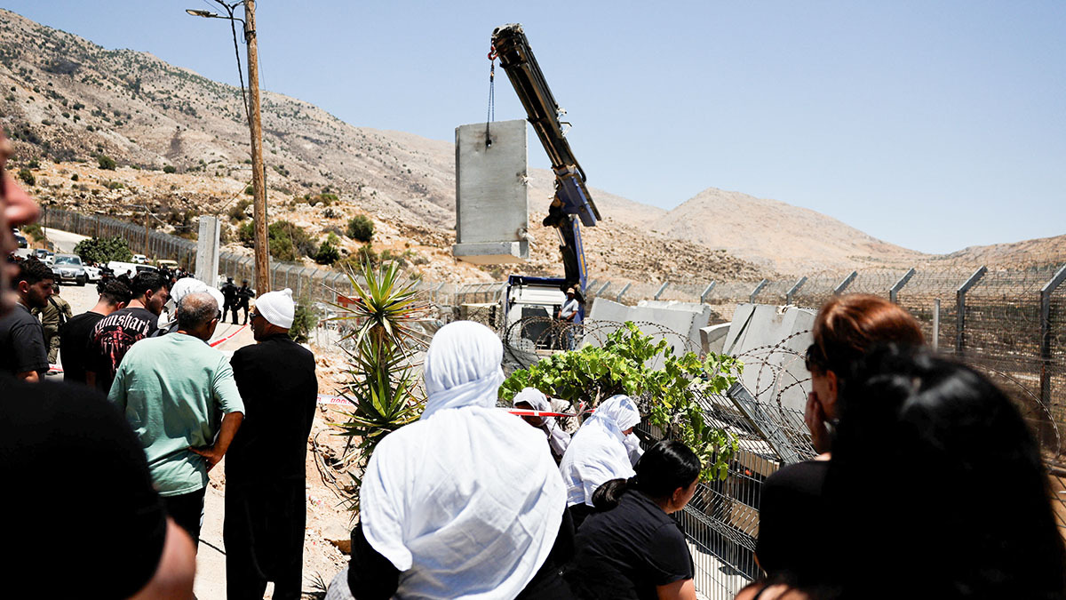 <p>Drusos observan cómo el Ejército israelí coloca un muro de hormigón en la línea de alto el fuego entre los Altos del Golán ocupados por Israel y Siria, en medio del conflicto en curso en las zonas drusas de Siria, en Majdal Shams, el 17 de julio de 2025 - REUTERS/ AMMAR AWAD </p>
