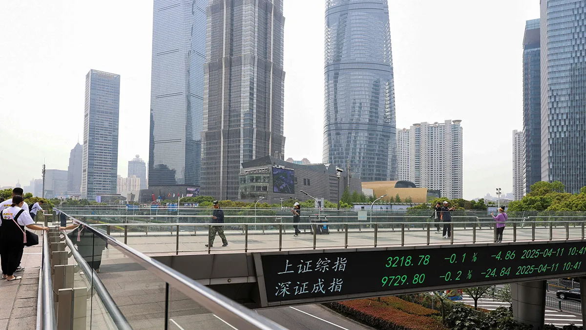 <p>Un tablero electrónico muestra los índices bursátiles de Shanghái y Shenzhen mientras la gente camina por un puente peatonal en el distrito financiero de Lujiazui en Shanghái, China, el 11 de abril de 2025 - REUTERS/ GO NAKAMURA</p>
