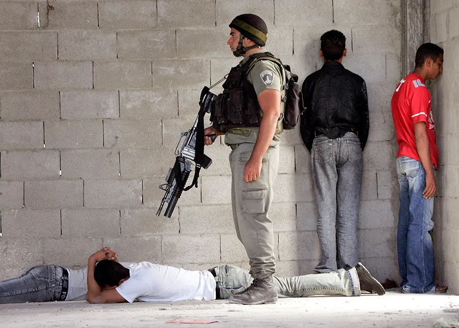 <p>Un policía fronterizo israelí vigila a palestinos detenidos durante una operación militar en la ciudad cisjordana de Hebrón el 11 de junio de 2005 - REUTERS/ NAYEF HASHLAMOUN</p>
