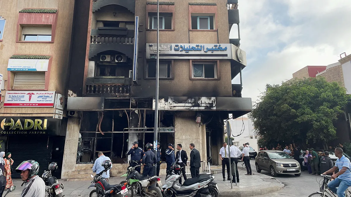 <p>Personas junto a un edificio incendiado que albergaba un banco, tras las protestas antigubernamentales lideradas por jóvenes, en Sale, Marruecos, el 2 de octubre de 2025 - REUTERS/ AHMED EL JECHTIMI </p>
