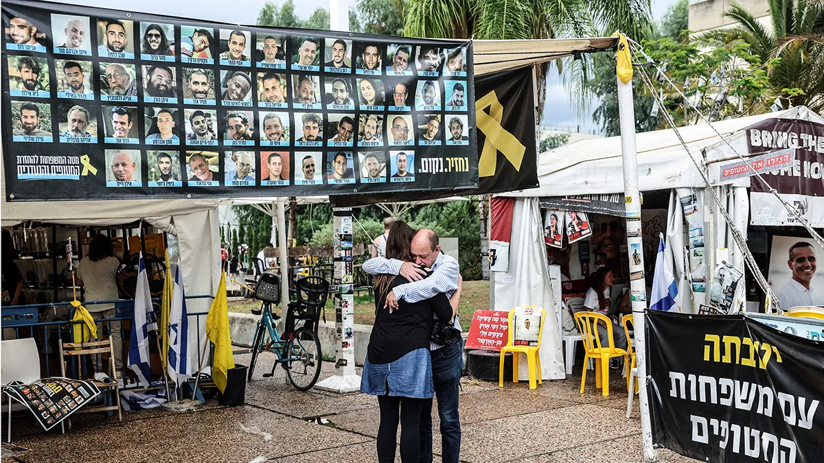 <p>La gente se abraza junto a una pancarta con fotos de rehenes en la plaza de los Rehenes, después de que el presidente de Estados Unidos, Donald Trump, anunciara que Israel y Hamás acordaron la primera fase de un alto el fuego en Gaza, en Tel Aviv, Israel, el 9 de octubre de 2025 - REUTERS/ RONEN ZVULUN</p>

