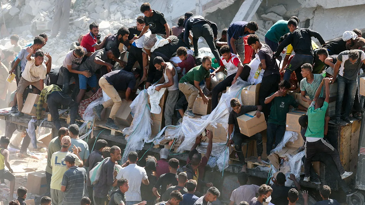 <p>Palestinos recogen ayuda humanitaria de un camión que entró en Gaza, en medio de un alto el fuego entre Israel y Hamás, en Khan Younis, en el sur de la Franja de Gaza, el 12 de octubre de 2025 - REUTERS/ RAMADAN ABED </p>
