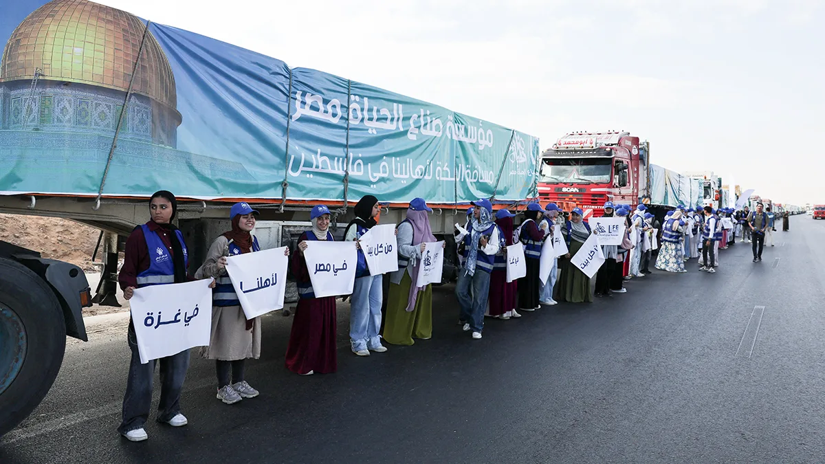 <p>Voluntarios egipcios sostienen carteles con la leyenda "A nuestra gente en Gaza" desde todos los hogares de Egipto junto a camiones cargados con ayuda humanitaria de la Alianza Nacional para el Trabajo de Desarrollo Civil, en Egipto, el 16 de octubre de 2025 - REUTERS/ AMR ABDALLAH</p>
