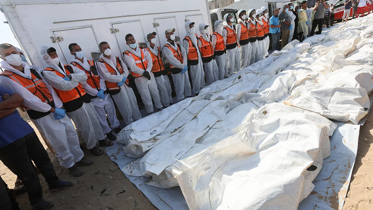 Palestinos permanecen cerca de los cuerpos no identificados mientras los preparan para su entierro en una fosa común, después de que Israel los entregara, en medio de un alto el fuego entre Israel y Hamás, en el Hospital Nasser en Khan Younis, en el sur de la Franja de Gaza, el 22 de octubre de 2025 - REUTERS/ RAMADAN ABED 