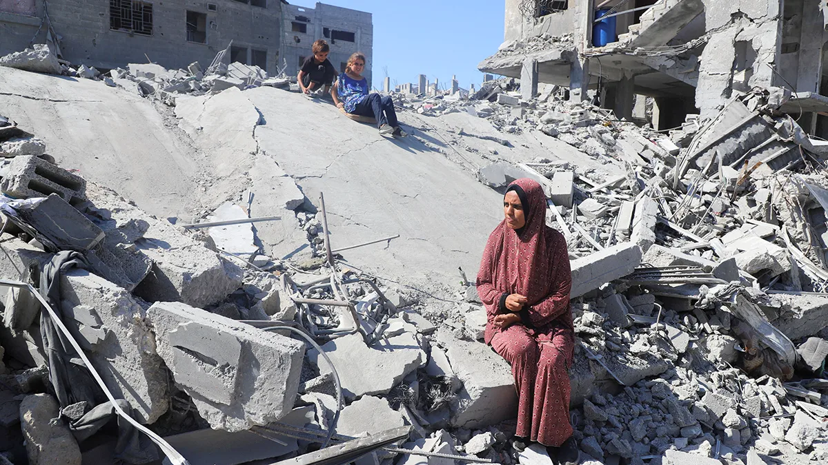 <p>La mujer palestina desplazada Amal Alyan y sus hijos se sientan sobre los escombros de las casas destruidas durante los ataques israelíes, en medio de un alto el fuego entre Israel y Hamás, en el campamento de Al-Shati, en la ciudad de Gaza, el 26 de octubre de 2025 - REUTERS/ EBRAHIM HAJJAAJ </p>
