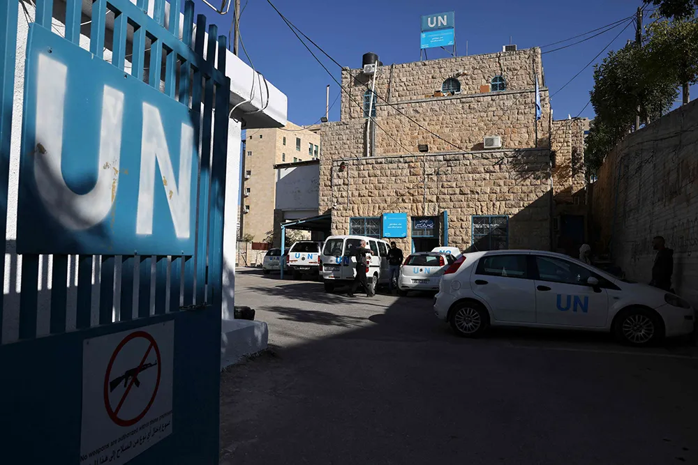 Personas caminan por la oficina central de la UNRWA en la ciudad ocupada de Hebrón, en Cisjordania, el 29 de octubre de 2024 - PHOTO/ ARCHIVO