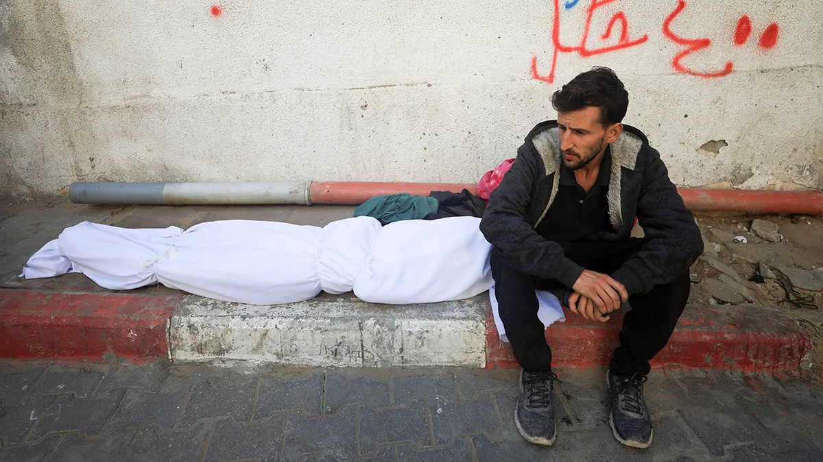 Un doliente se sienta junto al cuerpo de un palestino que, según los médicos, murió en los ataques israelíes nocturnos, en el Hospital Al-Shifa en la ciudad de Gaza, el 20 de noviembre de 2025 - REUTERS/ DAWOUD ABU ALKAS