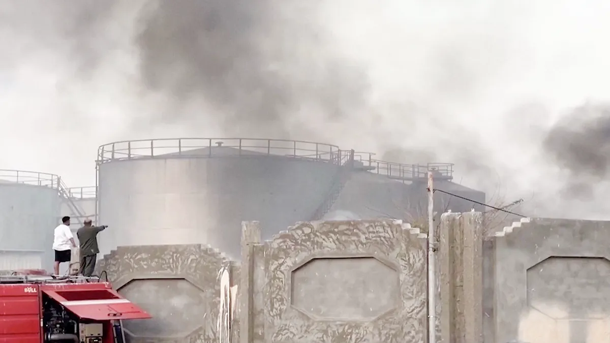 Una persona señala el humo que se eleva tras un ataque aéreo de la coalición liderada por Arabia Saudí, que tenía como objetivo lo que describió como apoyo militar extranjero a los separatistas del sur respaldados por los Emiratos Árabes Unidos, en el puerto meridional yemení de Mukalla, en esta captura de pantalla de un vídeo obtenido por Reuters el 30 de diciembre de 2025 - PHOTO/den al-Mustakillah TV/Distribuido por REUTERS