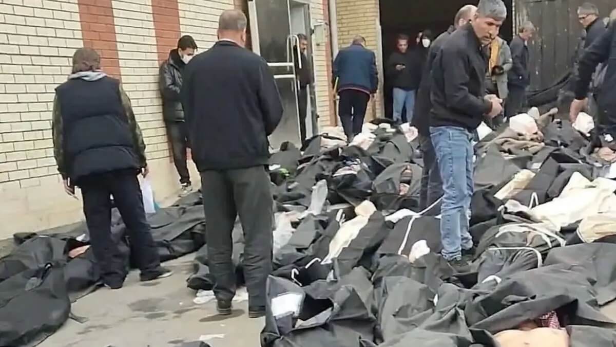 Cadáveres en bolsas mortuorias en el suelo mientras la gente observa la escena frente al Centro Médico Forense Kahrizak en Teherán
