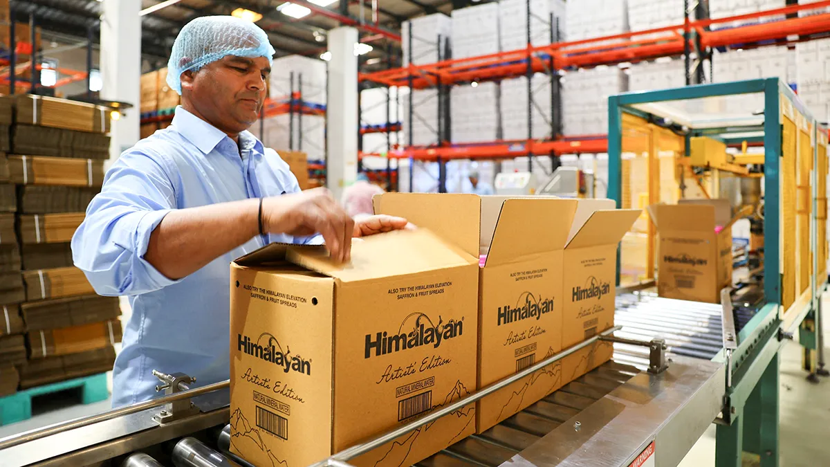 Un trabajador carga botellas de PET (polietileno tereftalato) llenas de agua natural en una caja de cartón en la planta embotelladora de agua mineral natural Tatas Himalayan en Dhaula Kuan, Himachal Pradesh, India, el 16 de octubre de 2025 - REUTERS/ ANUSHREE FADNAVIS